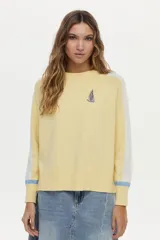 Sweater de punto color blanco con mangas raglán en azul y detalles en verde en los puños, cuello redondo y bordado de libélula en el pecho.