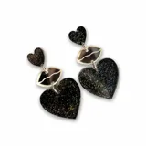 Aros colgantes con forma de corazón y labios, con glitter negro y detalles plateados.