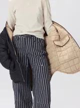 Campera reversible capitoneada con cierre frontal. Un lado es de color negro y el otro es de color beige, ambos con diseño acolchado. Cuenta con cuello redondo, mangas largas y bolsillos laterales.