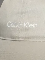 Gorra de béisbol color beige claro con logo de Calvin Klein bordado en blanco en el frente.