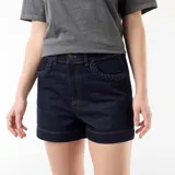 Short de jean azul oscuro, de tiro alto, con detalles trenzados en los bolsillos delanteros y vuelta en el ruedo.