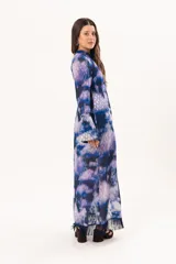 Vestido largo de manga larga con terminación campana, de color azul y violeta con estampado tie-dye, cuello mao con ojal y tajo frontal. Cuenta con flecos en el ruedo y tajo en la pierna.
