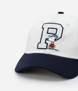 Gorra blanca de sarga con visera azul marino y bordado de Snoopy jugando baseball.