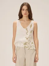 Top de lino color blanco con diseño holgado, escote en V y estampado abstracto en tono verde militar en el lateral izquierdo.
