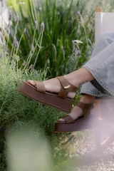 Sandalias de plataforma color negro, con diseño de dos tiras anchas en el empeine y cierre con velcro en el tobillo. Presentan una suela de plataforma alta y liviana.