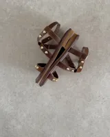 Sandalias planas de cuero negro con tiras decoradas con tachas metálicas doradas. Presentan una tira frontal sobre los dedos y una tira ajustable con hebilla alrededor del tobillo.