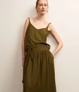 Pollera evasê midi color verde militar, confeccionada en crepé con cintura ancha con trabillas en los laterales y elástico detrás de la cintura. Incluye cinturón de cuerda para lazo con abalorios de puntas.