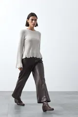 Pantalón de corte recto y pierna amplia confeccionado en símil cuero color marrón oscuro. Presenta una silueta estructurada con costuras verticales frontales que definen su diseño.