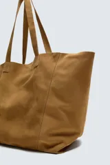 Bolso tipo shopper de piel con acabado serraje color camel, con dos asas de mano y bolsillo interior con cierre de cremallera.