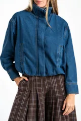 Campera bomber de jean azul con cierre frontal metálico, cuello alto y diseño oversize. Presenta costuras reforzadas y puños rectos.