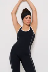 Mono deportivo de una pieza en color negro, con diseño de corte ajustado en el torso y piernas ligeramente acampanadas. Presenta detalles de líneas blancas contrastantes a lo largo de los laterales y en el escote, con espalda estilo nadadora.
