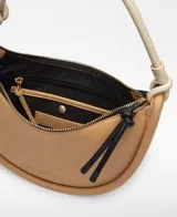 Bolso de hombro tricolor en forma de media luna, confeccionado en material sintético con textura granulada. Cuenta con un compartimento principal con cierre de cremallera, tirador con nudo negro, bolsillo interior con cremallera, asa corta tubular en tono claro con detalle metálico y logo grabado en la parte frontal.
