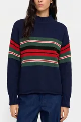 Sweater de punto con cuello alto, manga larga y puños acanalados. Presenta un diseño de rayas horizontales en tonos verde, rojo, negro y blanco sobre una base de color azul marino.
