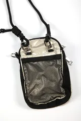 Cartera bandolera pequeña color dorado metálico, con cierre principal y bolsillo frontal con cierre. Tiene una correa ajustable de cordón negro y un parche rectangular negro con el logo "IND" en blanco.