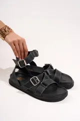 Sandalias negras de cuero con tiras anchas y hebillas plateadas.
