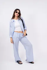 Pantalón largo de mujer, de corte amplio y tiro alto, con estampado a rayas verticales en tonos beige y blanco. Tiene cintura elástica con cordón ajustable.