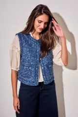 Chaleco capitoneado de jean azul con bordados florales en tono oscuro, cuello redondo y bolsillos delanteros aplicados con solapa fruncida.