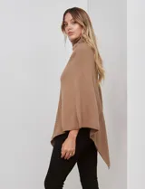 Poncho tejido color crema, con cuello polera y diseño trenzado diagonal en el frente. Presenta un corte asimétrico en el ruedo.