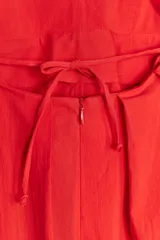Vestido largo rojo de Zara Woman Collection confeccionado en hilatura con mezcla de algodón. Escote pico y tirantes finos cruzados en la espalda ajustable con lazadas. Tiene bolsillos laterales, detalle de pliegues en la cintura y cierre en la espalda con cremallera oculta en la costura.