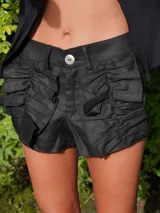 Short de lino negro con volados frontales decorativos, cierre frontal con botón y trabillas para cinturón.