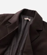 Sobretodo marrón de corte largo, con cuello de solapa, doble botonadura frontal y bolsillos con solapa en los laterales.