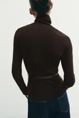 Jersey de punto liso confeccionado en 100% lana, con cuello subido y manga larga. Incluye un cinturón fino integrado a la altura de la cintura.