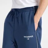 Pantalón de jogging New Balance color azul, de corte holgado y diseño recto. Cuenta con cintura elástica con cordón ajustable, bolsillos laterales y una línea vertical blanca a lo largo de la pierna. Presenta el logo de la marca bordado en el muslo.