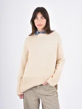 Buzo de tejido de punto color negro, con cuello redondo, mangas largas y puños anchos acanalados. Presenta un diseño con ruedo asimétrico y aberturas laterales.
