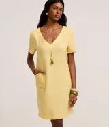 Vestido corto amarillo de viscolino, con escote en V, mangas cortas y bolsillos frontales aplicados.