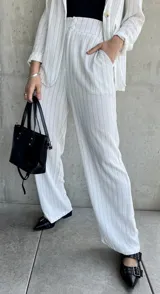 Pantalón blanco con finas rayas verticales negras, de corte palazzo y tiro alto.