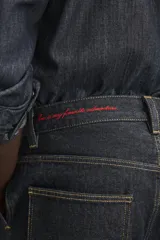 Pantalón chino de denim de algodón rígido, color índigo oscuro sin lavar. Corte baggy fit, tiro medio, con bolsillos frontales y traseros de plastrón. Presenta bordados a contraste en la cintura y en el bolsillo trasero.