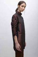 Vestido corto color marrón, de corte recto, con cuello alto, cierre frontal con cremallera y mangas largas con sistema de frunce. Confeccionado en tafeta tornasolada.