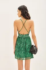 Vestido corto bretelero estampado con motivo de piel de reptil en tonos verdes, confeccionado en gasa con lurex y forrería a tono. Presenta un escote en V profundo con un aplique metálico, espalda baja con breteles cruzados regulables y elástico en la cintura.