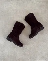 Botín de cuero vacuno color marrón oscuro, estilo cowboy o western, de caña media y taco bajo y ancho.