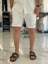 Bermuda blanca de tejido texturizado, con pequeño bordado oscuro en la parte inferior izquierda.