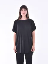 Blusa negra de manga corta con cuello redondo y textura plisada. El corte es holgado y la prenda se combina con un pantalón a juego del mismo material y textura.