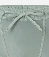 Bermuda deportiva para hombre, color verde menta, con short de compresión integrado. La bermuda exterior es suelta y tiene un pequeño logo estampado en el muslo izquierdo.