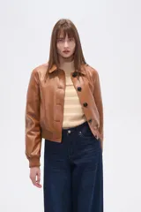 Chaqueta estilo bomber corta de eco-cuero color caramelo, con cuello camisa, cierre frontal de botones oscuros y puños y cintura de tejido acanalado.