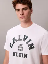 Remera de algodón blanca de corte regular con cuello redondo y mangas cortas. Presenta un estampado gráfico frontal con el logotipo de Calvin Klein en tono oscuro.