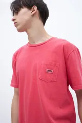 Remera celeste de algodón con bolsillo en el pecho, teñida en prenda. Tiene una etiqueta en el bolsillo y un estampado en la espalda.
