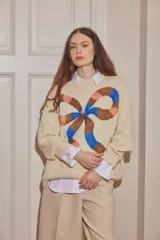 Sweater de lana color crudo, con diseño de moño grande estampado en el frente en tonos marrón, azul y rosado. Presenta cuello redondo, mangas largas con puños acanalados y corte holgado.