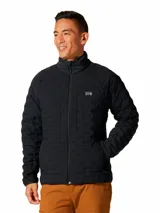 Campera técnica de Mountain Hardwear con aislamiento de plumón, diseñada con tejido elástico para mayor libertad de movimiento. Presenta cierre frontal completo, cuello alto, bolsillos laterales con cierre y diseño acolchado con patrón geométrico.