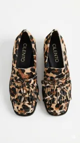 Mocasín de cuero con estampado animal print tipo vaca, de horma cuadrada. Presenta detalle de flecos y lazo decorativo en el empeine, con taco bajo cuadrado.