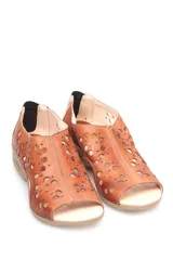 Sandalia baja de cuero color beige con diseño calado de círculos de distintos tamaños en la capellada. Cuenta con una suela de goma con cámara de aire en el talón y cierre posterior.
