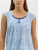 Pijama compuesto por remera sin mangas con escote redondo, botones frontales y detalle de puntilla, acompañado de un pantalón capri con cintura elástica. Presenta un estampado floral en tonos rosados sobre base gris.