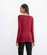 Suéter de punto color rosado, con cuello barco, mangas largas y puños con botones decorativos. El dobladillo también es acanalado.