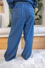 Pantalón de denim azul de calce relajado y fluido, decorado con pequeñas perlas aplicadas en toda la superficie con mayor densidad en el ruedo. Presenta pinzas frontales, bolsillos laterales y cierre de botón.