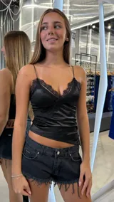 Top lencero negro de satén con escote en V y detalles de encaje en el busto. Tiene tirantes finos.