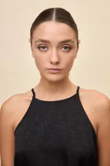 Top negro de calce relajado y textura satinada, con escote halter y lazo fino para ajustar en la cintura.