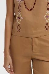 Top de lino color tostado, con escote cuadrado, tirantes anchos y bordados decorativos en el pecho.